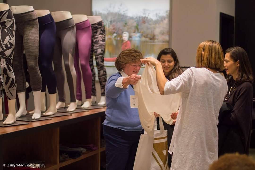 A group of people inspecting clothes and holding a YS bag within a store.