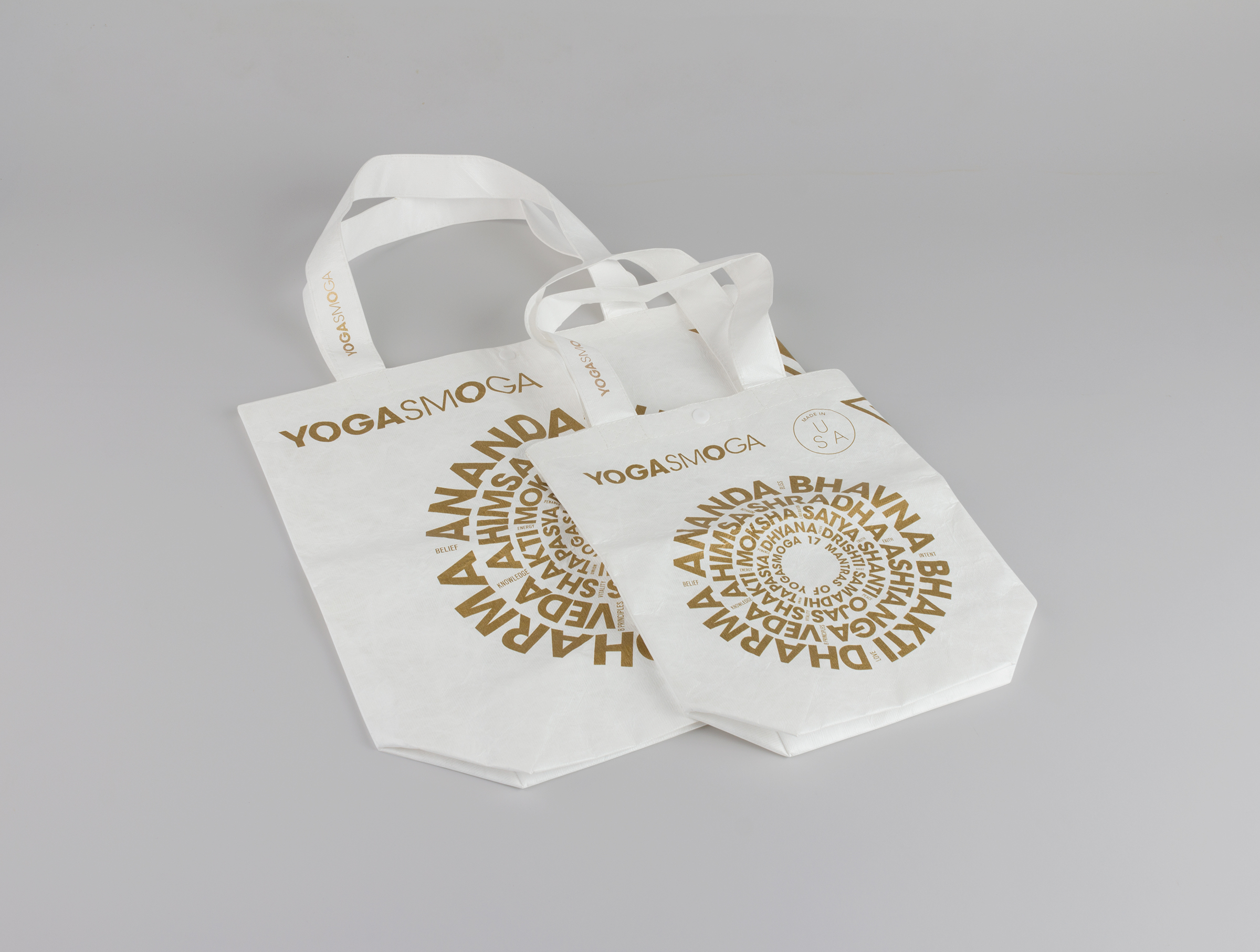 YOGASMOGA hoilday retail bags in two sizes, showing Sanskrit words arranged in concentric circles, lying flat.