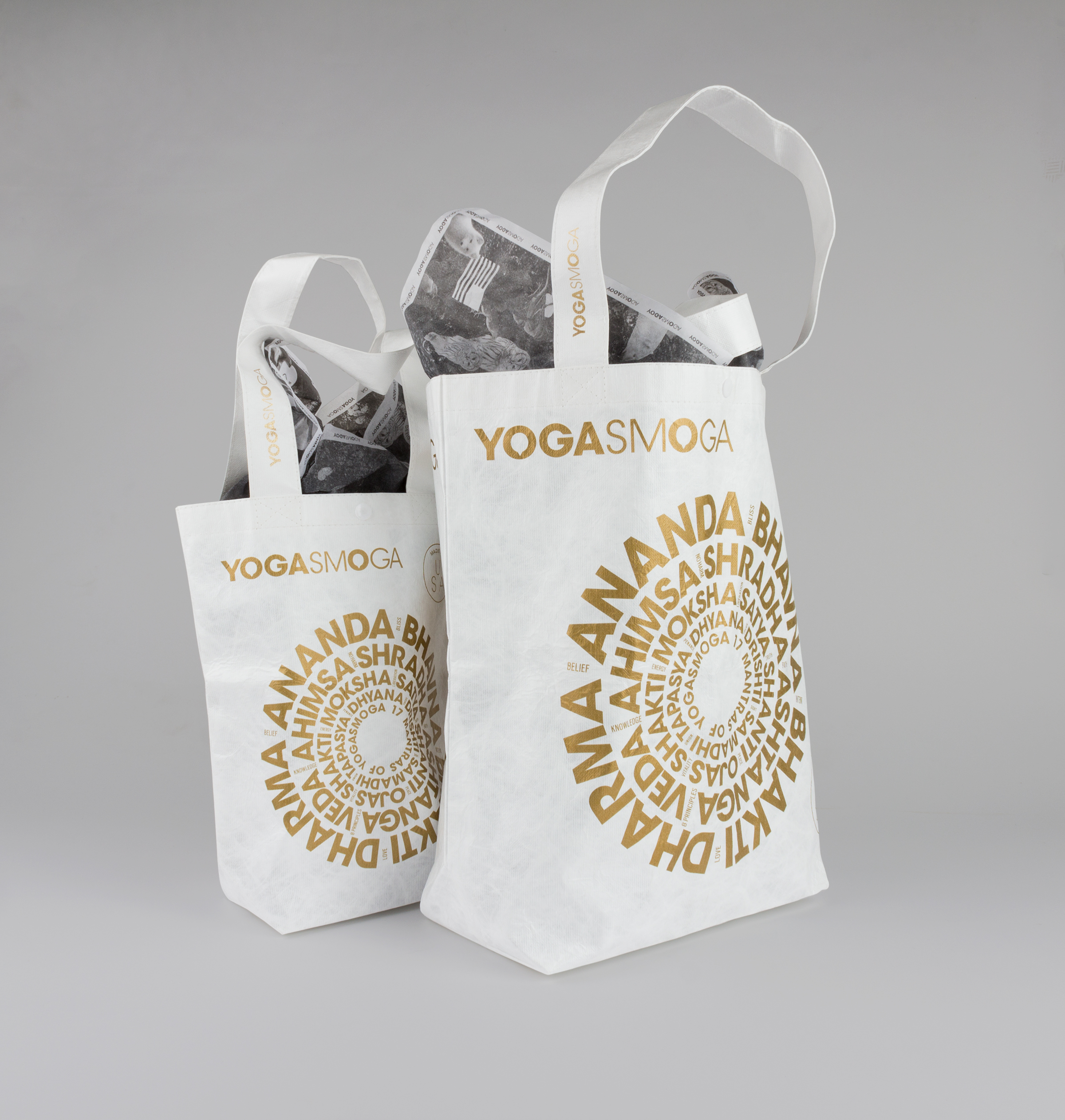 Front of Gold and White YOGASMOGA hoilday retail bags in two sizes, showing Sanskrit words arranged in concentric circles.