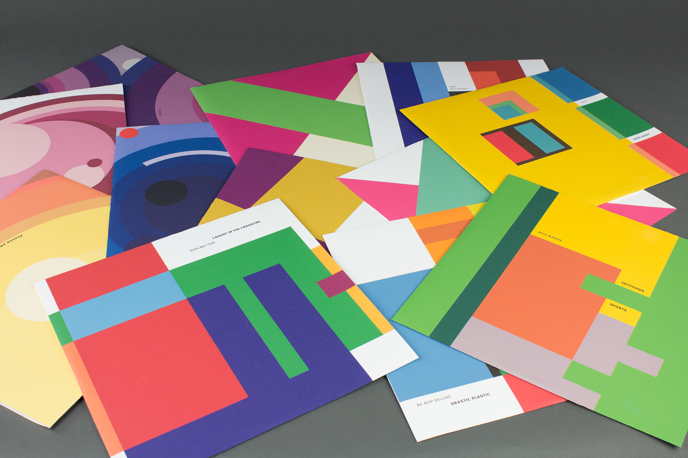 Several album covers spread out on a table, each with abstract color fields on each cover.